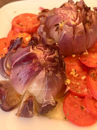 CebollaFlorTomate2 Plato con cebolla asada en forma de flor y rodajas de tomate, regado con vinagreta, lista para servir.